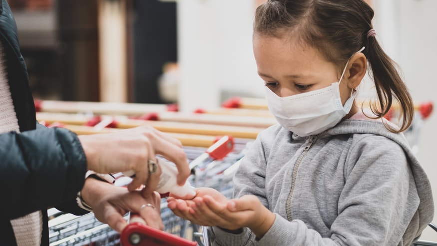 Mother pouring hand sanitizer on her daughter's hands