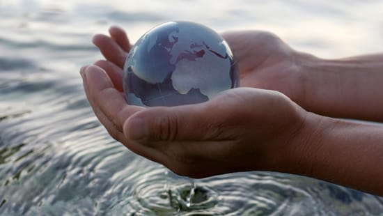 Holding globe in two hands over water