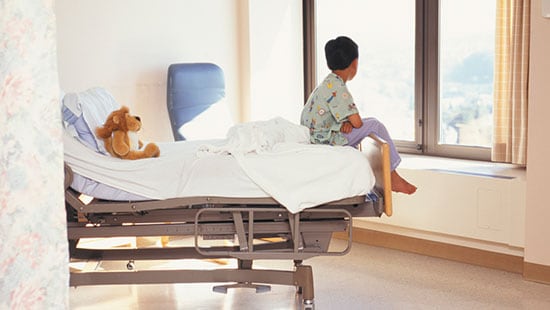 Krankenhäuser und chirurgische Praxen – Junge sitzt im Bett und sieht aus dem Fenster