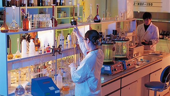 Ecolab expert in laboratory setting with lab coat and protective eyewear, mixing chemicals.