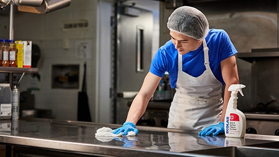 Food Service employee cleaning with an Ecolab product